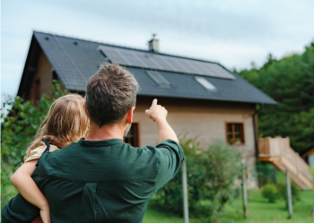 father and daughter looking at solar panels on house roof
